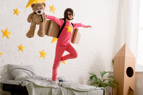 Preview: Kid with teddy bear standing on bed on one leg