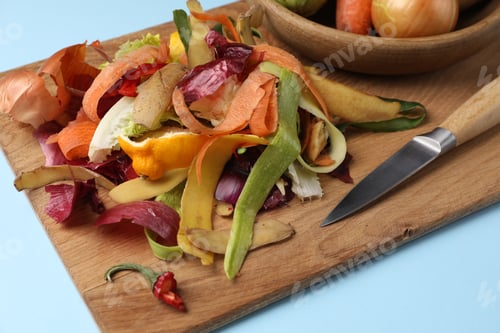 Preview: Different fresh vegetables with peels and knife on light blue background, closeup