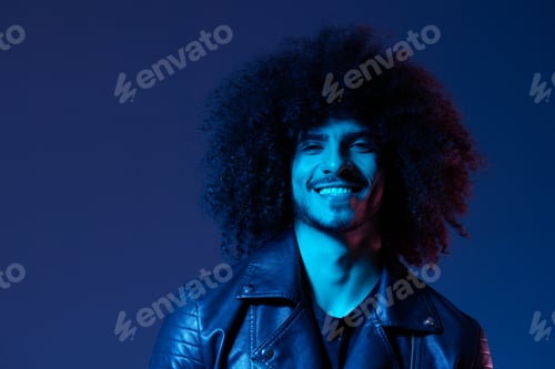 Preview: Portrait of fashion man with curly hair on blue background multinational, colored light, black