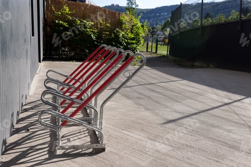 Preview: Metal empty bicycle parking near the wall of the house. A sports field in the background.