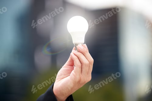 Preview: Hands, light bulb and idea in the city for solution, eco friendly or renewable energy on blurred ba