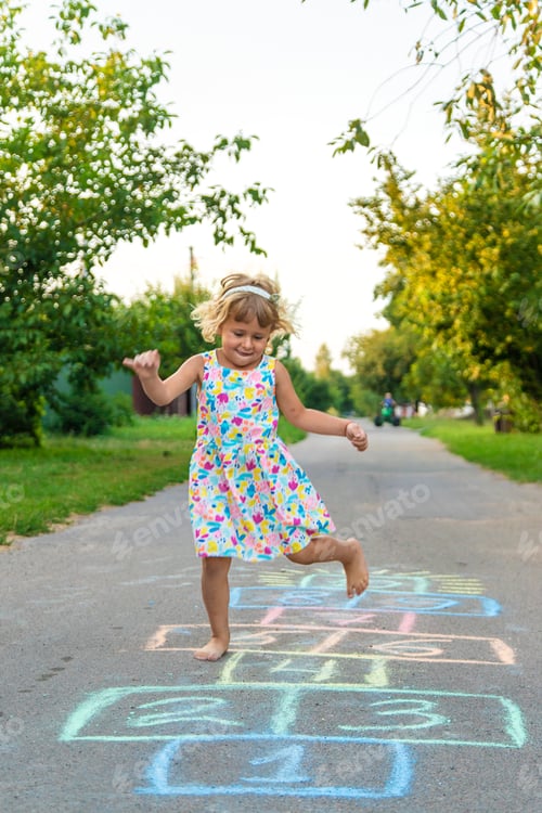 Preview: Children jumping hopscotch on the street. Selective focus.