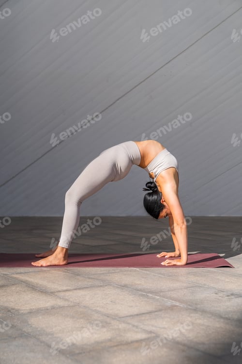 Preview: Brunette woman doing Urdhva Dhanurasana or Upward Bow pose on a yoga mat.
