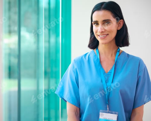 Preview: Portrait Of Mature Smiling Female Doctor Wearing Scrubs In Hospital