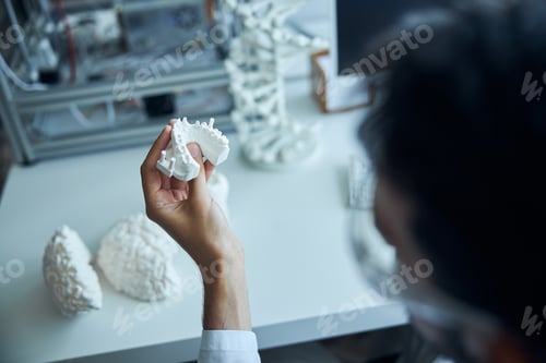 Preview: Dark-haired medical student examining the plastic denture