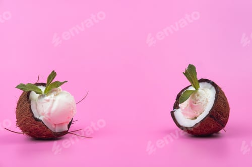Preview: Vanilla ice cream balls in fresh coconut halves decorated with mint leaves on a pink background