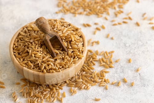 Preview: Bowl of raw dry rye grain with a wooden spoon on white table close up