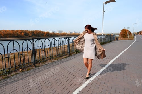 Preview: a confident young attractive woman in a coat high-heeled shoes walks through the streets of the city
