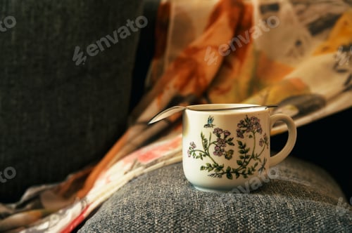Preview: Cup of coffee on the rim of gray sofa
