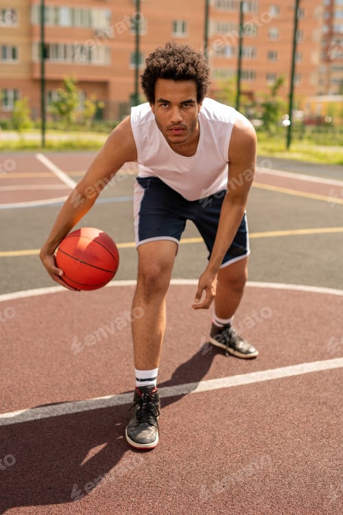 Preview: Serious young basketball player going to throw ball while standing by white line