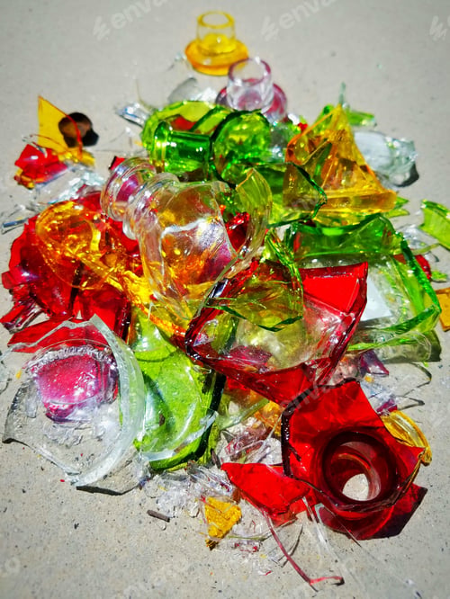 Preview: Vertical abstract of sunlight hitting colorful broken glass on cement.