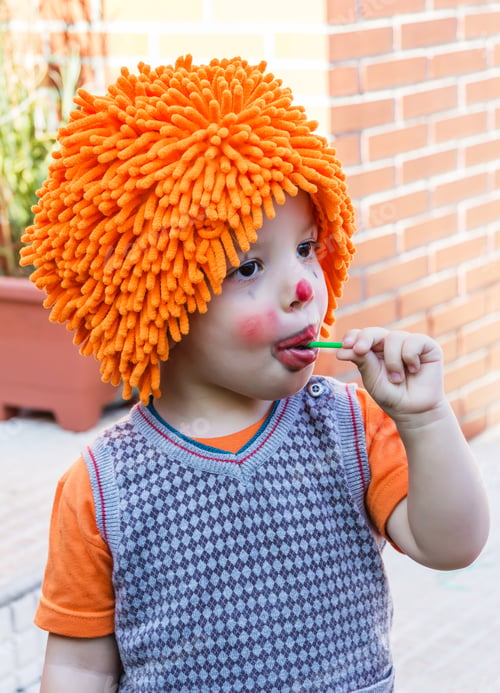 Preview: Clown child eating lollipop in a party