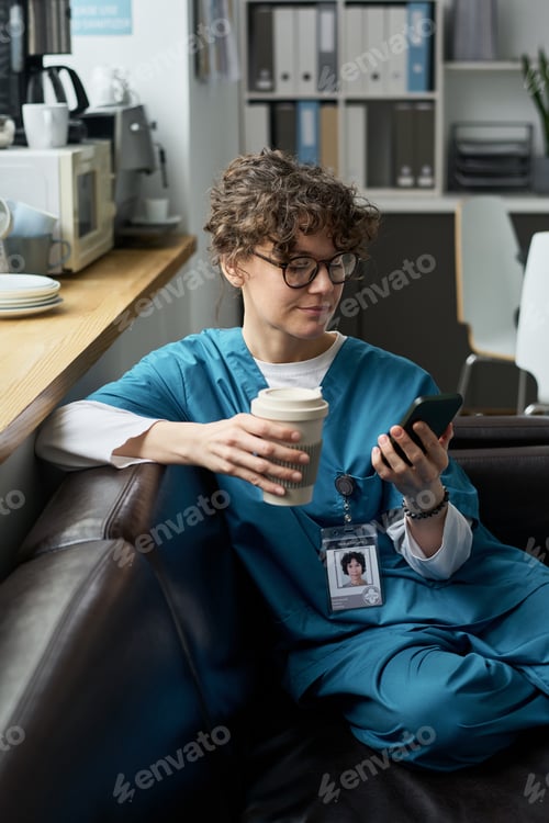 Preview: Medical Professional Checking Smartphone While Holding Coffee