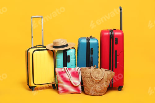 Preview: Many colorful suitcases, beach bags and straw hat on orange background