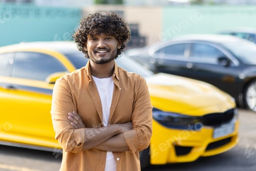 Preview: Portrait of a young smiling hispanic man against the background of a sports yellow car. He is