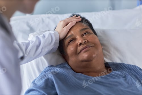 Preview: Smiling senior woman looking at nurse while laying on hospital bed