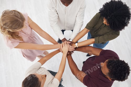 Preview: Group of five businesspeople stacking their hands together in an office at work. Business professio