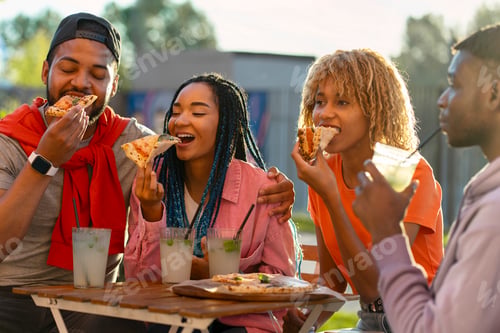 Preview: miling stylish African American friends eating pizza, drinking lemonade sitting together in cafe