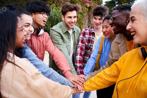 Preview: Multirracial group of cheerful students holding hands outdoors. Multi-ethnic young boys and girls