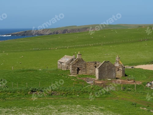 Preview: View of a traditional stone farmhouse located in a hilly, green valley on the coast