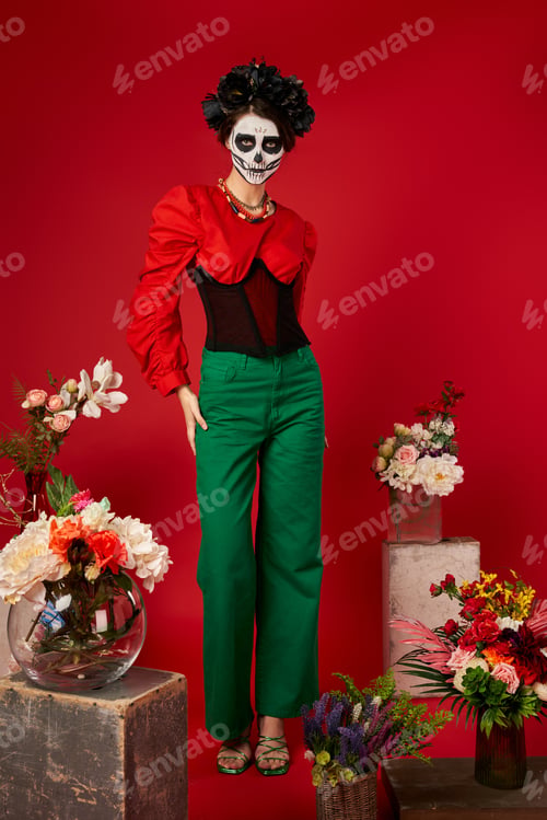 Preview: woman in sugar skull makeup near traditional dia de los muertos ofrenda with bright flowers on red