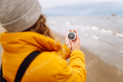 Preview: Woman traveler looking for directions with a compass on beach. Active lifestyle. Adventure concept.
