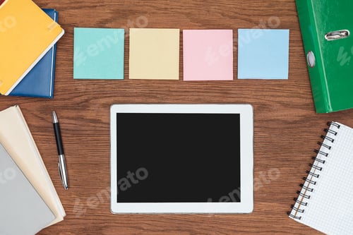 Preview: top view of four sticky notes and digital tablet with blank screen on wooden office desk