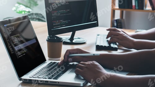 Preview: Young programmer writing program code sitting at the workplace with computer in the office.