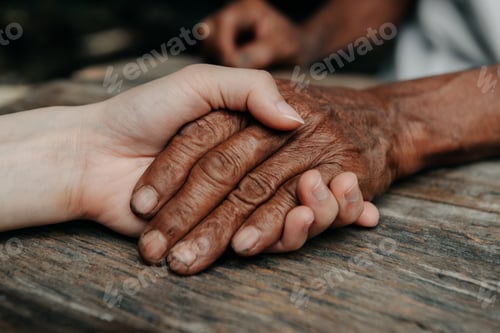 Preview: Hands of the old man and a woman hand on the wood table in sun light