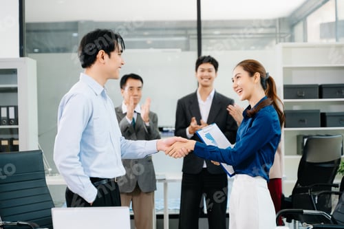 Preview: Asian business professionals shaking hands and celebrating success in a modern office,