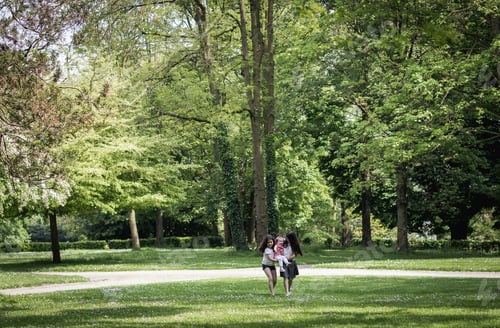 Preview: Two girls carry a baby in their arms in the park on a summer day.