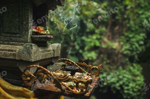 Preview: Traditional balinese Canang Sari offerings to gods and spirits with flowers, food and smoky