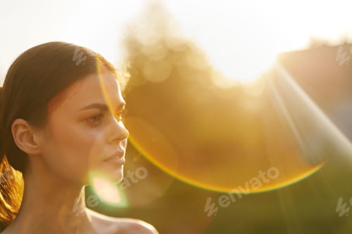 Preview: Young woman with long hair in natural sunlight, exuding peace and serenity, against a warm sunset