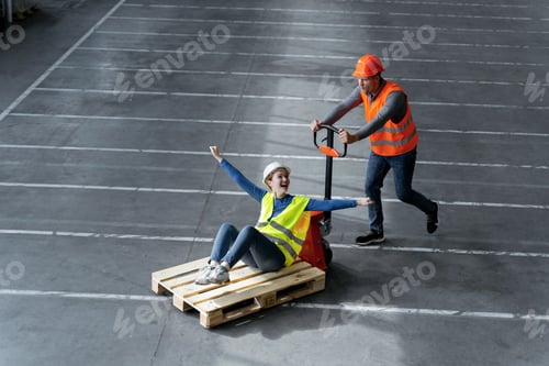 Preview: Smiling workers wearing protective helmets, vests, factory man transports his colleague on forklift