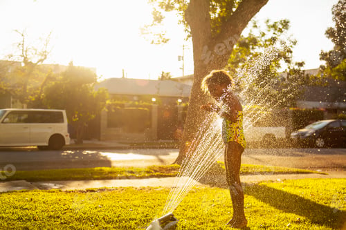 Preview: Girl standing in garden sprinkler