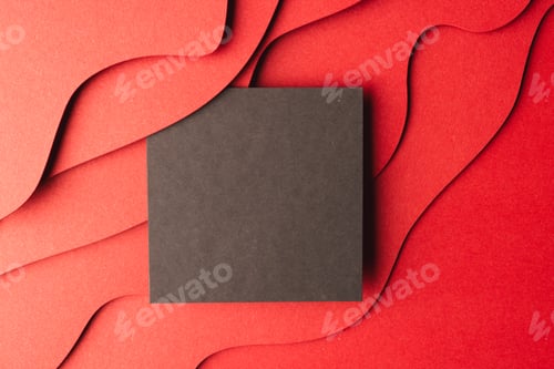 Preview: Square of black paper with copy space on red waves of paper on red background