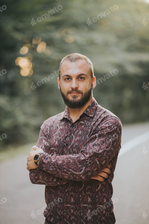 Preview: Handsome Caucasian male posing with crossed arms in the woods