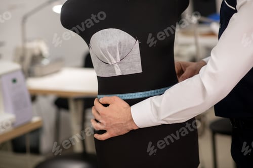Preview: Hands of male fashion designer measuring dummy waist