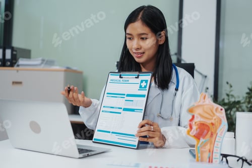 Preview: An Asian female doctor uses a respiratory system model while working a computer,planning treatment