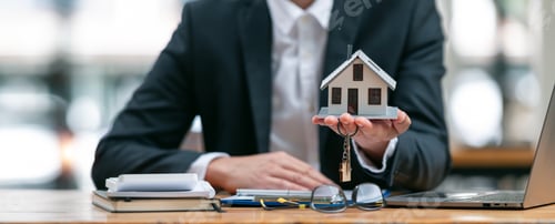 Preview: Businessman or real estate agents holding house model offering to his client.