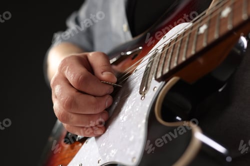 Preview: Man playing guitar with mediator on black background, closeup