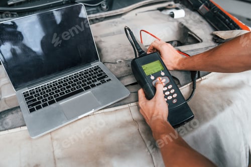 Preview: Close up view of man's hands that holding device for testing automobile in salon