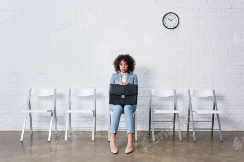 Preview: Tense businesswoman with briefcase sitting on chair and waiting