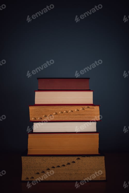 Preview: tall stack of five books against dark blue