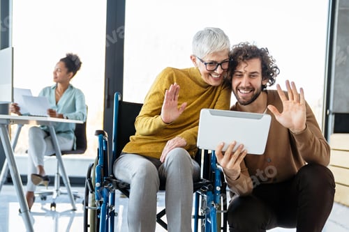 Preview: Disabled woman in wheelchair looking at computer, discussing startup project with interracial team