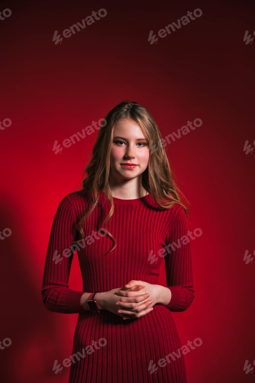 Preview: Portrait pretty positive smiling teen girl in stylish red dress over red background look at camera