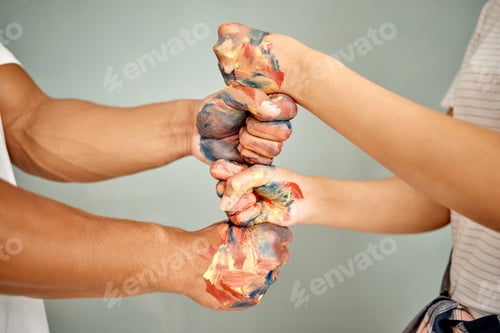 Preview: Cropped shot of a young couple standing with their fists stacked while painting