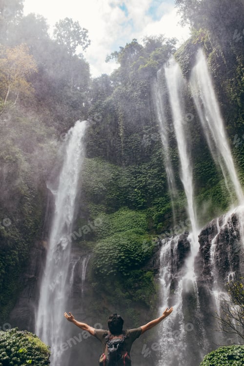 Preview: Young man standing by waterfall