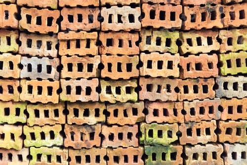 Visualização: Tijolos coloridos antigos empilhados no chão. Fundo abstrato.