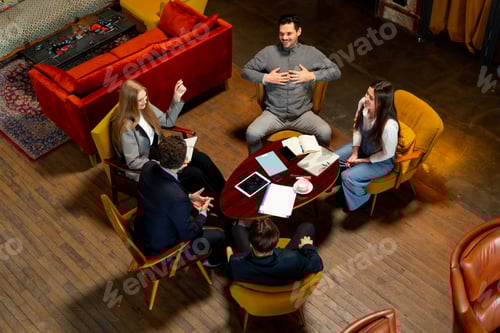 Preview: top shot in large beautiful hall office employees sitting on yellow chairs discuss a deal